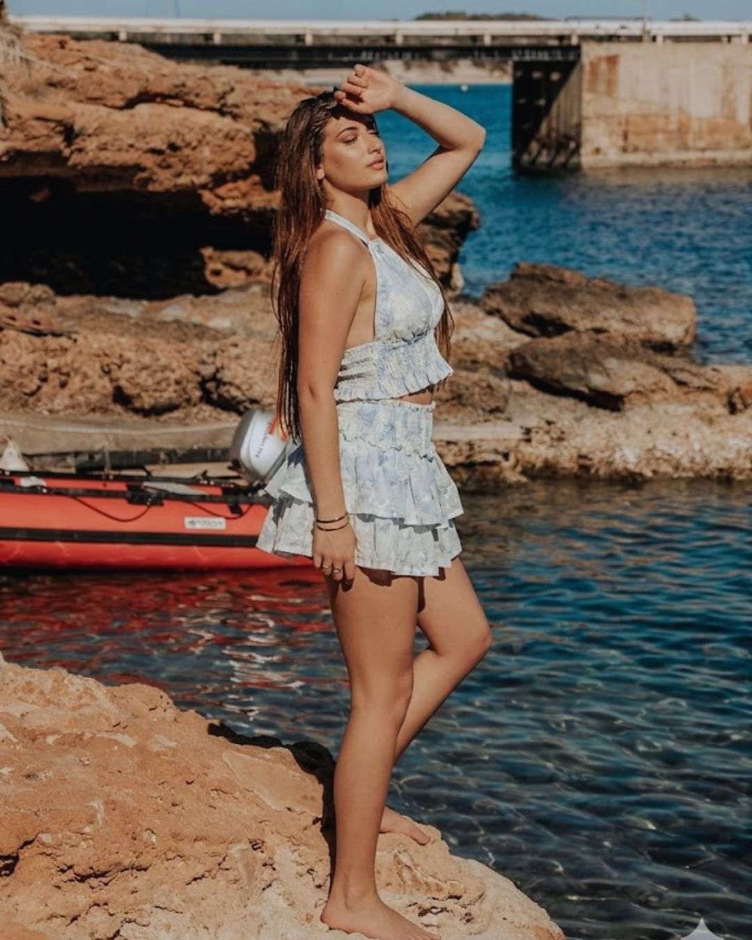 Mujer luciendo el conjunto halter falda acuarela azul en un entorno costero elegante.