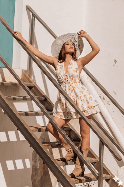 Modelo usando un vestido corto artesanal blanco bordado mientras sube escaleras bajo la luz del sol.
