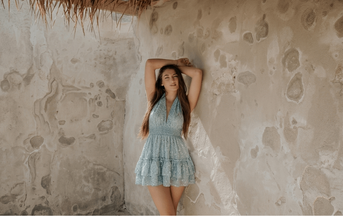 Vestido corto ibicenco encaje lentejuelas azul en mujer, fondo de pared clara y natural, estilo fresco y elegante.