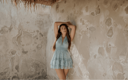 Vestido corto ibicenco encaje lentejuelas azul en mujer, fondo de pared clara y natural, estilo fresco y elegante.